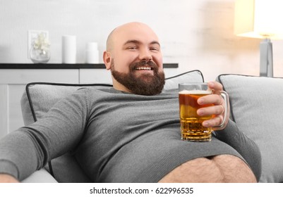 Man Holding Glass Of Beer On His Big Belly At Home