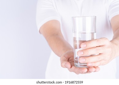 Man Holding Glass Of Water Isolated Grey Background. Clean Drinking Water In Clear Glass.