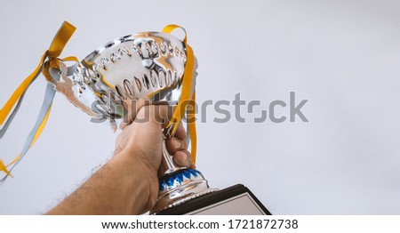 a man holding up a gold trophy cup on white background