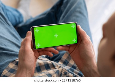 Man holding a green screen smart phone with both hand, with mock up green screen at nigh - Shutterstock ID 2271318765