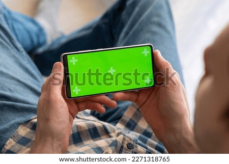 Man holding a green screen smart phone with both hand, with mock up green screen at nigh