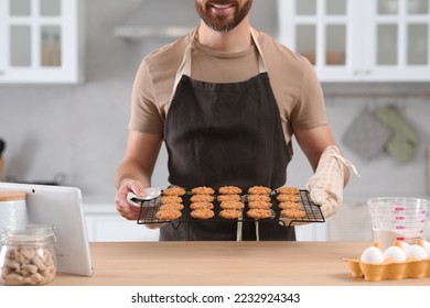 Man holding grid with freshly baked cookies in kitchen, closeup. Online cooking course - Powered by Shutterstock