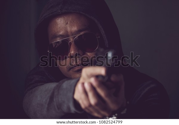 Man holding a gun aiming at the camera. Women\
violence. Abused and tortured concept. Human trafficking concept.\
Stop violence against Women. International women\'s Day. Stop\
abusing violence.