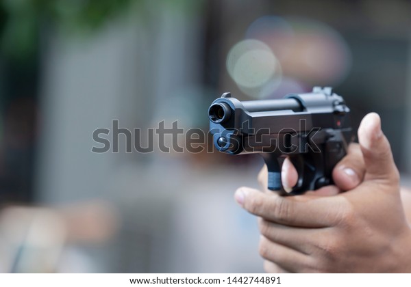 Man holding gun aiming\
pistol in hand ready to shoot. The criminal robber or gangster\
thief  concept