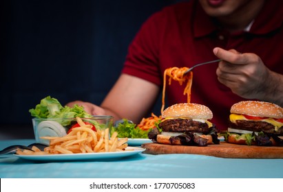 Man Holding Hamburger On The Wooden Plate After Delivery Man Delivers Foods At Home. Concept Of Binge Eating Disorder (BED) And Relaxing With Eating Junk Food.