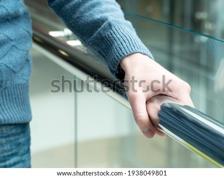 Man holding a hand rail in mall staircase closeup. Stock photo of the guy walking on the staircase