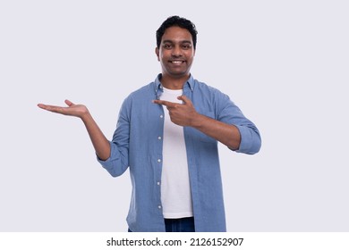 Man Holding Hand To Side Pointing At It Watching To Camera Isolated. Indian Man Smilling. Commercial, Advertisment Concept