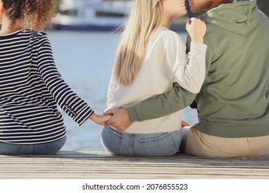 Man Holding Hands With Another Woman Behind His Girlfriend's Back On Pier Near River, Closeup. Love Triangle