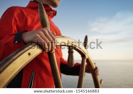 Man Holding Hands on ship rudder and navigates.
