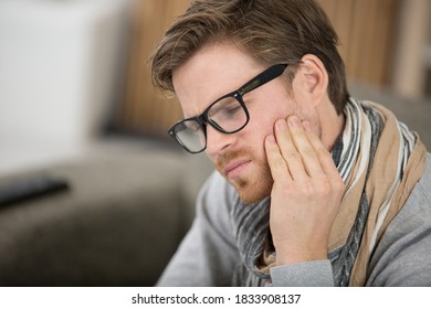 man holding his cheek with hand suffering from bad toothache