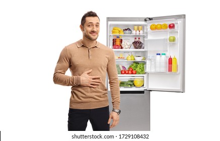 Man Holding His Hand On His Stomach And Standing In Front Of A Full Refrigerator Isolated On White Background