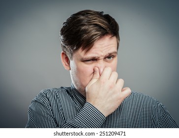 Man Holding His Nose Against A Bad Smell