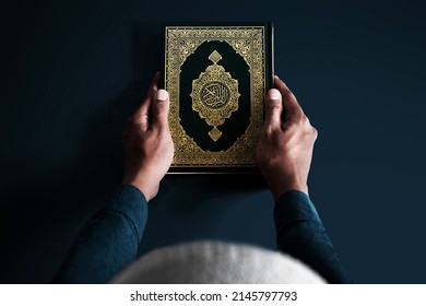 Man holding holy book on dark background