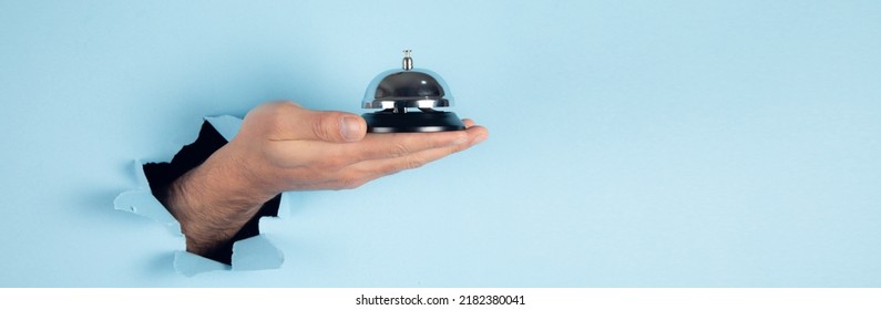 Man Holding Hotel Ring Bell On Blue Background