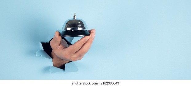 Man Holding Hotel Ring Bell On Blue Background