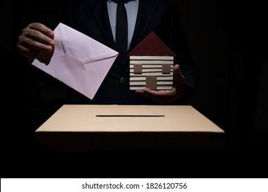 Man Holding House And Voting Envelope In His Hand. Voting For The Economy. Civic Duty.