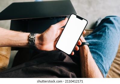 Man Holding IPhone 13 Pro With A White Screen Mock Up While Sitting On A Sofa. Rostov-on-Don, Russia - November 1 2021