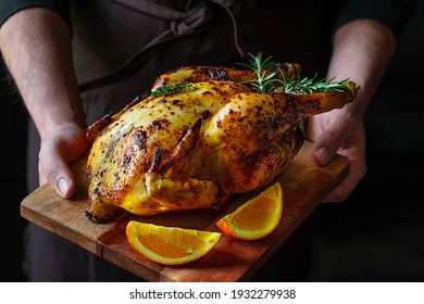 A man holding a juicy roasted chicken with mustard, honey and oranges with herbs - Powered by Shutterstock