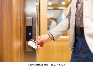 Man Holding Key Card On Sensor To Open Elevator Door In Modern Building Or Hotel.