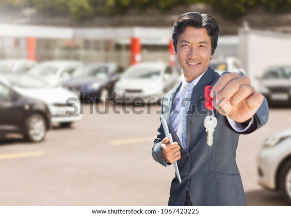 Man Holding key in front of\
cars