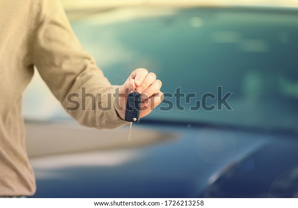 Man holding key in modern auto dealership, closeup.\
Buying new car