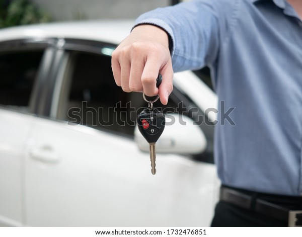 Man holding key in modern auto\
dealership. Close up hand of cardealer giving car key to customer.\
Car dealer with a key. Auto dealership and rental\
concept