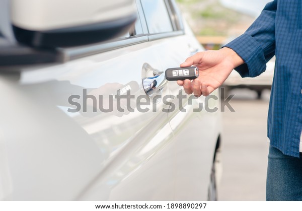 Man holding key opening car\
door