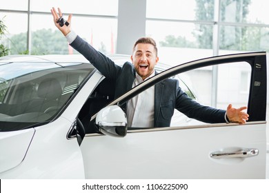 Man Is Holding A Key Of Their New Car, Looking At Camera And Smiling.