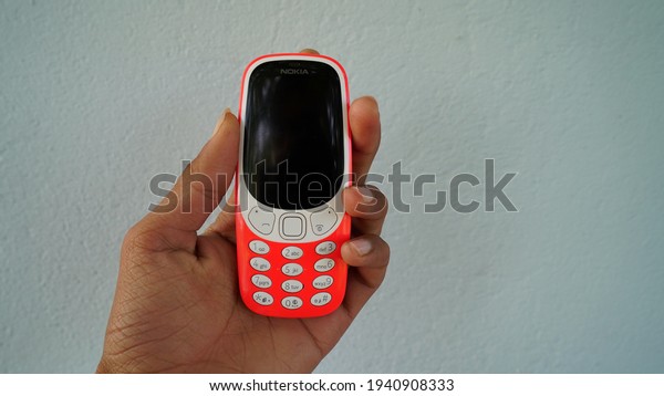 A man holding a keypad mobile phone with\
black screen isolated on white background. Smartphone key dialing\
in hands. Technology and social\
concept.