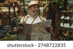 Man holding a large folded map and looking up in a building clothing shop, wearing pith helmet and backpack straps; curiosity travel exploration.