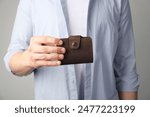 Man holding leather business card holder on grey background, closeup