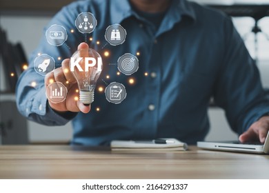 The Man Is Holding Light Bulb. Key Performance Indicator (KPI) Using Business Intelligence (BI) Metrics To Measure Achievement Versus Planned Target, Person Touching Screen Icon, Success.