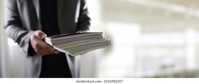 man holding a magazine publication page media stack to stack communication research data to learn advertising and banner space objects - Shutterstock ID 2316985257