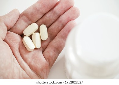 A Man Holding Magnesium Taurate Tablets In His Hand. Close Up.