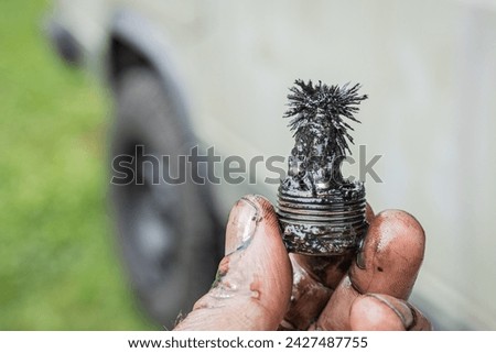 Man holding a magnetic plug or screw of a gearbox in hand, with visible shaving metal parts bonded on magnet. Scary thing in a new gearbox but quite normal on an old one