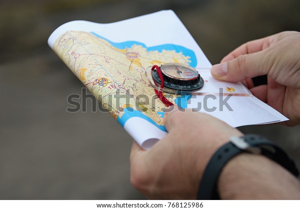 Man holding\
map.Athlete uses navigation equipment for orienteering,compass and\
topographic map
