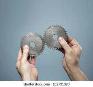 A Man Holding A Matching Pair Of Old Cog Gear Wheels In His Hands.