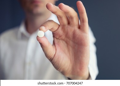 Man Holding Medicine. Hand Of Person Showing White Pill Towards Camera. 