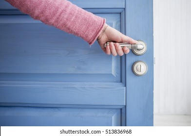 Man Holding A Metal Pen In An Open Wooden Door Blue