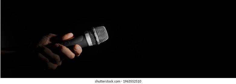 A Man Holding A Microphone On A Black Background
