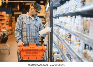 Hombre sosteniendo botella de leche en el supermercado.