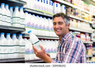 Man Holding Milk Bottle In The Supermarket And Smiling At The Camera