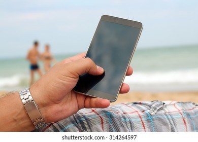 Man Holding A Mobile Phone. Internet Connection On The Beach. Sea Behind