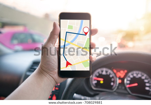 man holding mobile phone with map gps navigation\
application in the car