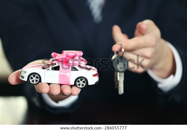 Man holding\
model of car and keys in his\
hands