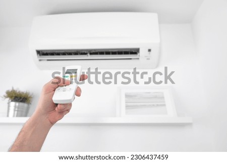 Man holding a modern AC unit remote.