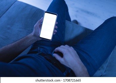 Man Holding Modern Smartphone / Cellphone And Watching XX Videos On A Home Couch. Taboo Still In Modern Times.