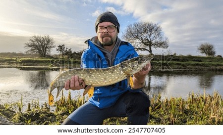 Man holding Northern pike freshwater fish caught in Cregg river, Galway, Ireland, water animals and wildlife, nature background, fishing, catch and release	