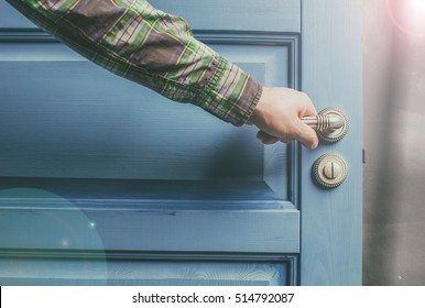 Man Holding On To By Its Metal Handle In The Open Wooden Door Blue