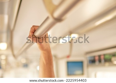 man holding on to the safety bar of an empty train car in daylight